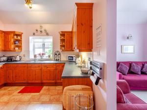a kitchen with wooden cabinets and a pink couch at Nightingale in Temple Combe