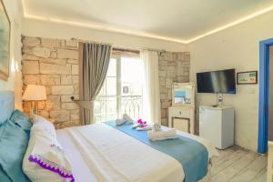 a bedroom with a large bed and a television at Alacati Asmali Konak Hotel in Alaçatı