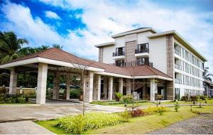 a large white building with a porch on a street at Jamins Hotel in Ibajay