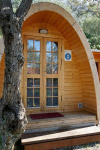 Cabaña de madera con puerta arqueada junto a un árbol en Campeggio Gianna Golfo dei Poeti en Lerici