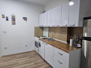 une cuisine avec des placards blancs et un comptoir en bois dans l'établissement AL Apartments 02, à Prizren