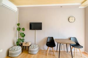 a dining room with a table and chairs and a tv on the wall at Airport Garden Room in Čilipi