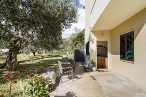 un patio con mesa y sillas junto a una casa en Airport Garden Room, en Čilipi