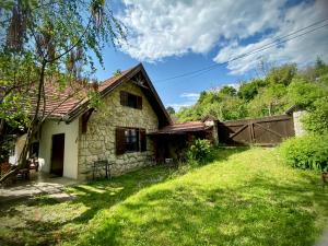 una vieja casa de piedra con un patio de césped en Almáskert Vendégház, en Mónosbél