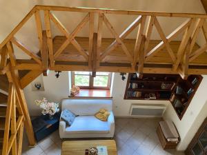 Habitación en el ático con sofá blanco y techo de madera. en Almáskert Vendégház, en Mónosbél