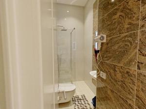 La salle de bains est pourvue de toilettes et d'une douche en verre. dans l'établissement Matteo's Apartments, à Velipojë
