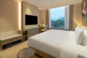 - une chambre avec un grand lit blanc et une grande fenêtre dans l'établissement Hyatt Place Linyi People Square, à Linyi