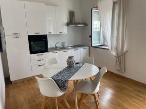 una cucina bianca con tavolo e sedie bianche di Atlantide holiday apartments a Castellammare di Stabia