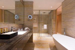 y baño con 2 lavabos, bañera y ducha. en Sheraton Zhanjiang Hotel en Zhanjiang