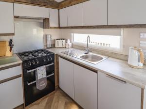 a kitchen with white cabinets and a sink and a stove at 5 Wilkinson Way in Lincoln