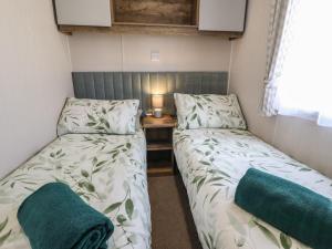 two twin beds in a small room with a table at 5 Wilkinson Way in Lincoln