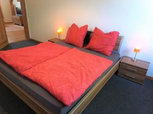 a bedroom with a large bed with red sheets and pillows at Ferienhof Schönberg in Lindow