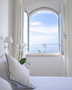 una camera da letto con finestra affacciata sull'oceano di Relais La Ghinghetta a Portoscuso