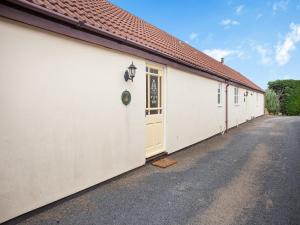 a row of white buildings with a yellow door at Robin Cottage in Temple Combe