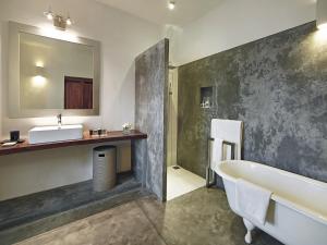 ein Badezimmer mit einer Badewanne, einem Waschbecken und einem Spiegel in der Unterkunft The Fort Printers in Galle