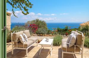a patio with a couch and a table and the ocean at The Yiameli Collection - Meli in Skinária +8 photos