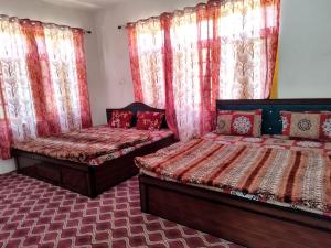 two beds in a room with red curtains at Hotel city way in Srinagar