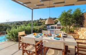 a dining room with a table and chairs on a patio at The Yiameli Collection - Yasmi in Skinária +7 photos