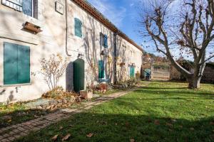 un edificio blanco con puertas verdes y un patio de césped en Véritable Mas Provençal À La Palud, en La Palud-sur-Verdon