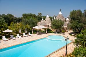 a pool at a resort with chairs and umbrellas at Trulli Boccadoro in Ostuni