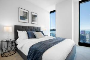 een slaapkamer met een groot bed en grote ramen bij Stunning City Views 2 bed 2 bath- Ur Urban Oasis！ in Melbourne