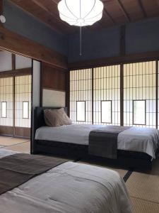 1 dormitorio con 2 camas, lámpara de araña y ventanas en ビラ里山双林 en Inashiki