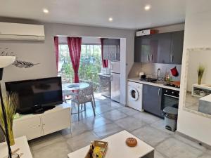 eine Küche und ein Wohnzimmer mit einem großen TV in der Unterkunft au cœur des pins in Cap d'Agde