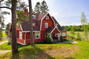 une maison rouge avec des arbres devant elle dans l'établissement Hotelli Siuntio, à Sjundeå