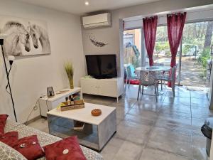 ein Wohnzimmer mit einem Sofa, einem TV und einem Tisch in der Unterkunft au cœur des pins in Cap d'Agde