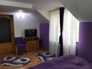 Cette chambre violette comprend un lit et une fenêtre. dans l'établissement Pensiunea Rebeca, à Bughea de Sus