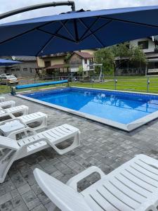 a pool with white lounge chairs and an umbrella at Фенікс in Yaremche