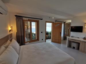ein Schlafzimmer mit einem großen weißen Bett und einem TV in der Unterkunft Peninsula Gardens Hotel in Kaş