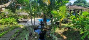 a backyard with a pool with a waterfall and trees at Rambutan Hotel in Lovina
