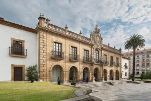 un grand bâtiment avec un palmier en face dans l'établissement Eurostars Hotel de la Reconquista, à Oviedo