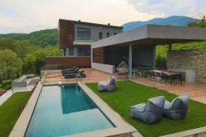 un patio trasero con piscina y una casa en #SKGH Arbitrage Hyperluxe Villa -near Pozar Baths & Kaimaktsalan mountain 