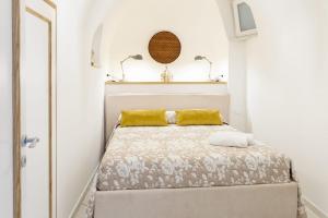 a small white bedroom with a bed with yellow pillows at Casa Borgo Sant'Angelo in Sant'Angelo D'Ischia