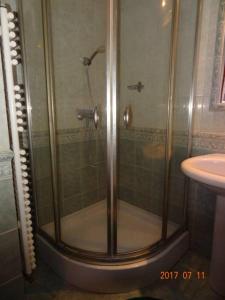a shower with a glass door next to a sink at Orsolya apartman in Nyíregyháza