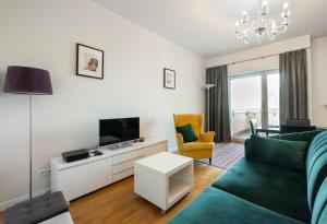 a living room with a green couch and a tv at Mokotów 2-Bedroom Premium Apartment in Warsaw