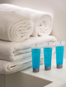 a group of towels and moisturizers on a shelf next to towels at Mokotów 2-Bedroom Premium Apartment in Warsaw