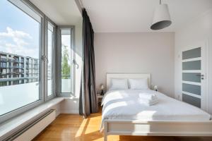 a white bedroom with a bed and a large window at Mokotów 2-Bedroom Premium Apartment in Warsaw