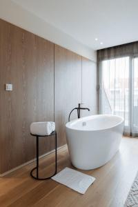 La salle de bains est pourvue d'une baignoire blanche et d'une fenêtre. dans l'établissement Cosmopolite Hotel Nieuwpoort-Bad, à Nieuport