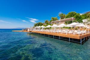 Doria Hotel Bodrum-City Center في بيتيس: رصيف به كراسي ومظلات على الماء
