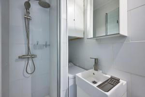 a white bathroom with a sink and a shower at Un Balcon sur la Mer - Appt à 30m de la plage in Saint-Aubin-sur-Mer +10 photos
