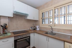 a kitchen with white cabinets and a sink and windows at Casa Siloam in Torrox Costa