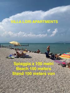 een groep mensen op een strand met de oceaan bij Villa Lori Apartments Garden and Beach in Peschiera del Garda