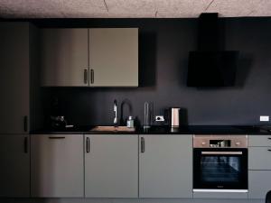a kitchen with white cabinets and a black wall at Studio Apartment / Unique Location / Stunning View in Tórshavn