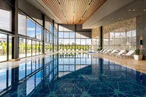 a swimming pool in a building with chairs and windows at The Fortyfive Business Hotel & Spa in Manisa