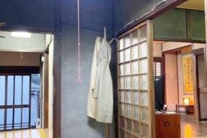 um roupão branco pendurado numa parede num quarto em おとまりどころ下関本町 em Shimonoseki