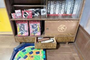 uma estante de livros com jogos e caixas no chão em おとまりどころ下関本町 em Shimonoseki