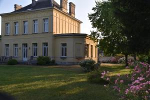 uma casa grande com uma árvore e flores no quintal em Petit château à la campagne. em Beloeil